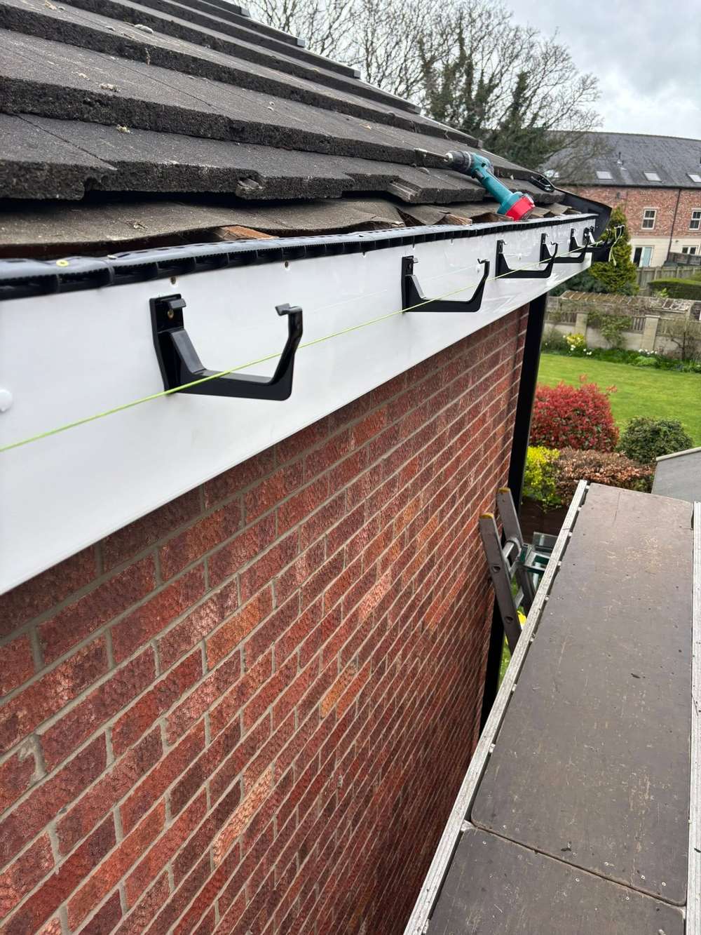 Gutter brackets on a new white fascia, lined up against a green string line