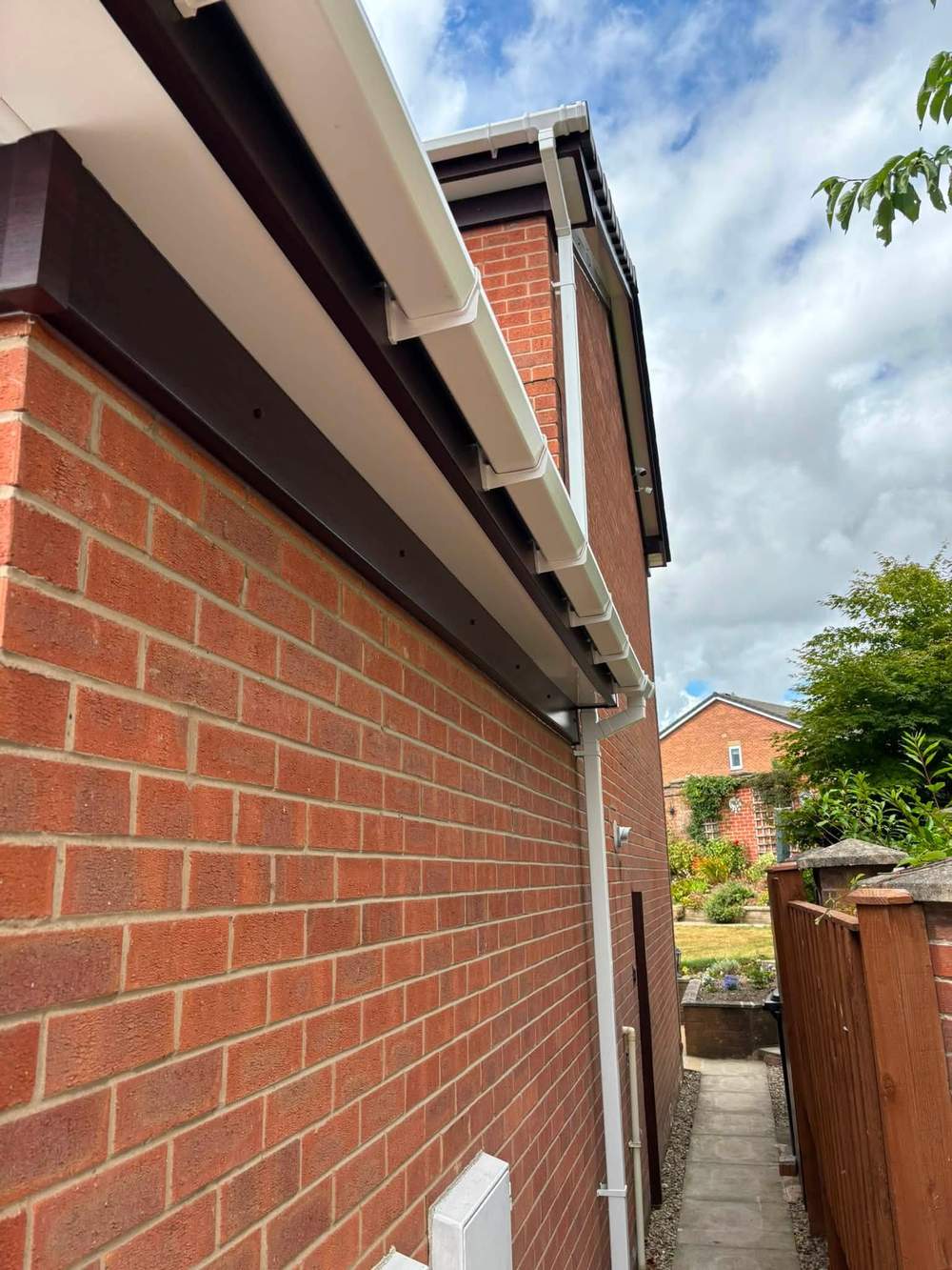 White fascia and soffit along a red brick side wall