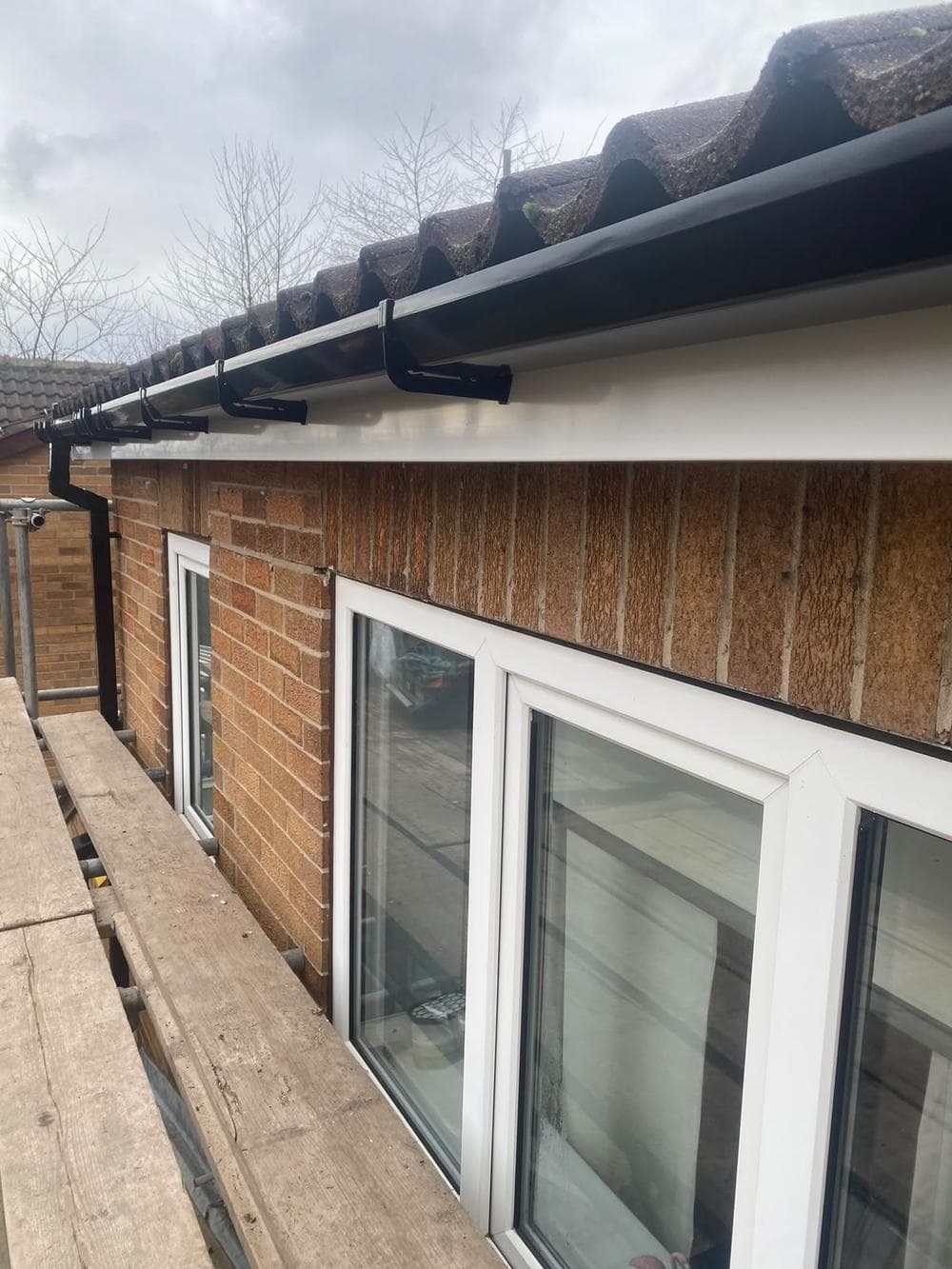 The finished roofline over the patio doors: white fascia and a new black gutter