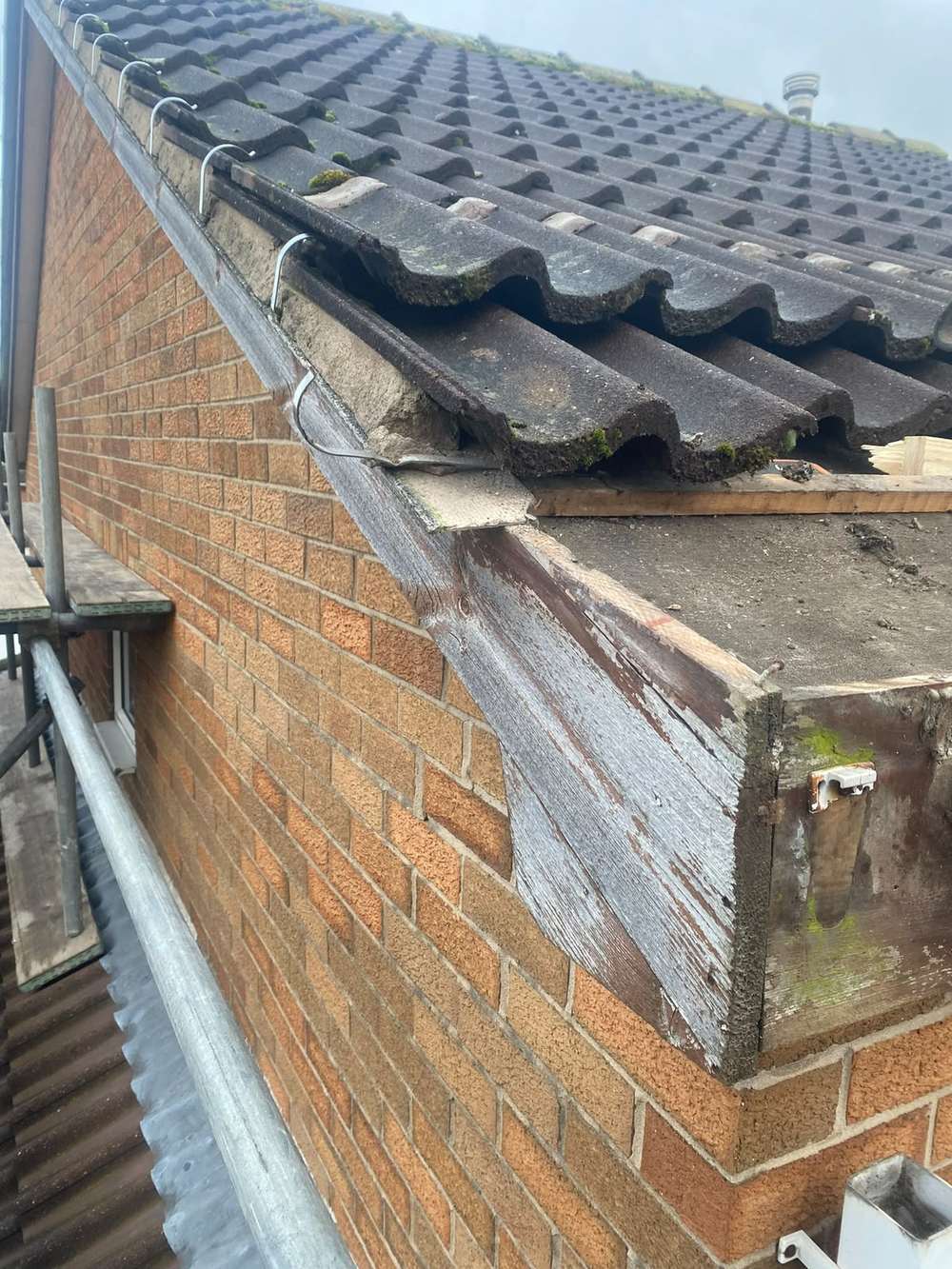 Rotten boxed eaves corner with the paint gone, before