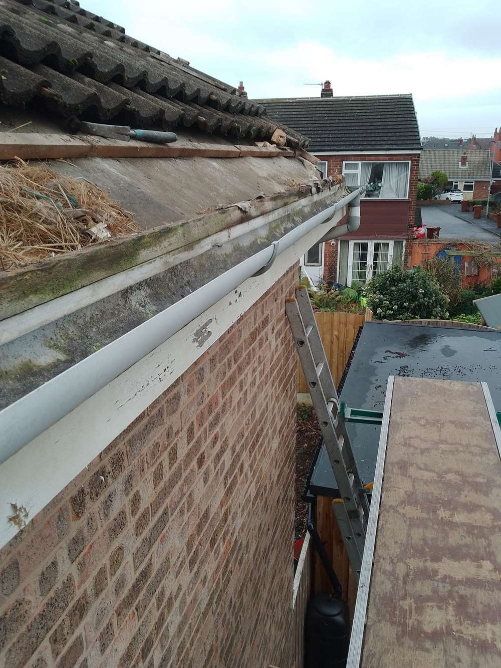 Old dirty gutter along the eaves of a brick house