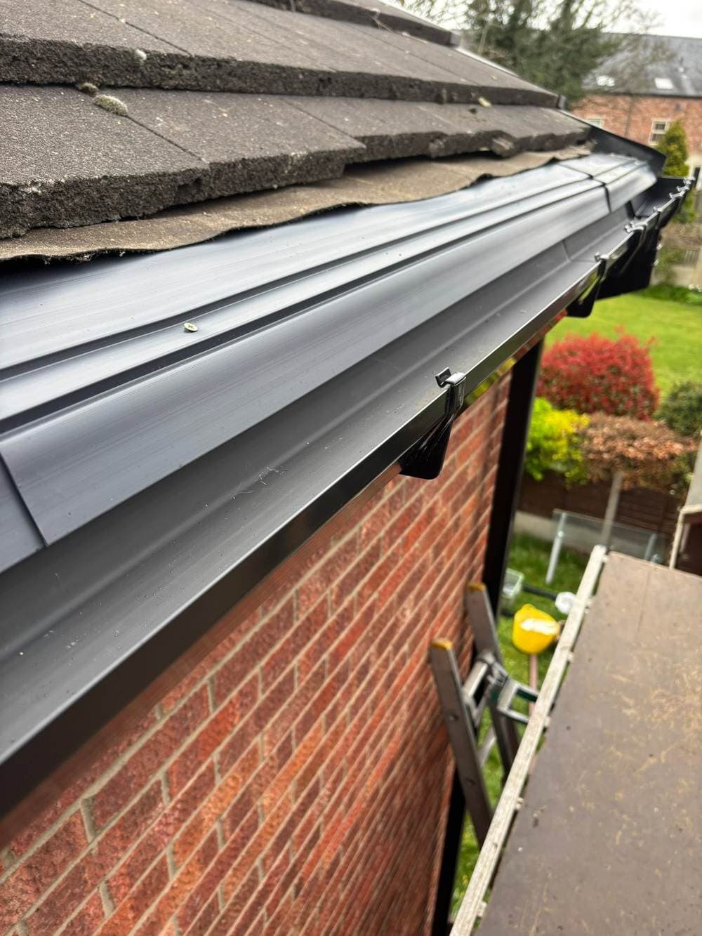 Grey gutter on a new fascia along a brick house
