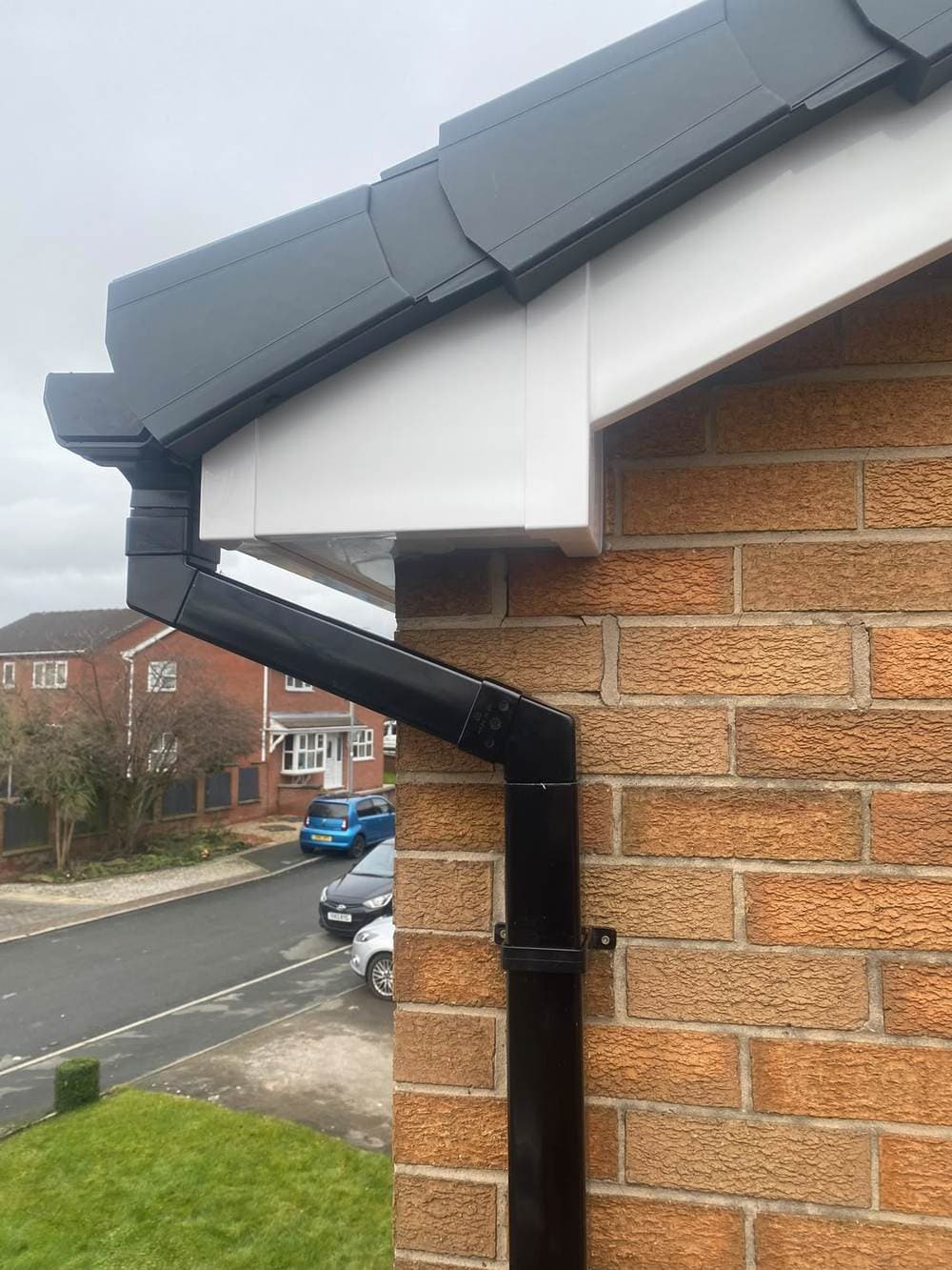 Rebuilt boxed eaves corner in white with a black downpipe and anthracite verge